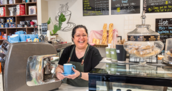 Enza from Spizzico holiding a coffee cup in front of an espresso coffee machine